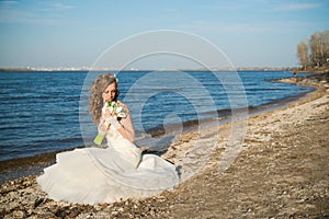 Beautiful bride in a white dress on coast of river