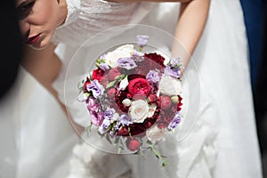 Beautiful bride in white dress holding wedding bouquet closeup