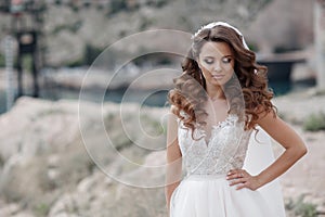 Beautiful bride in white dress posing on sea and mountains in background