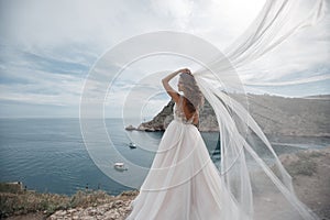 Beautiful bride in white dress posing on sea and mountains in background