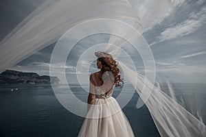 Beautiful bride in white dress posing on sea and mountains in background