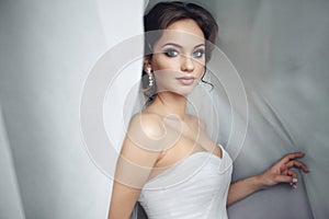 Beautiful bride in white dress posing under curtain