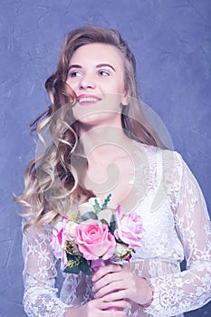 Beautiful bride in a white peignoir with a bouquet of flowers