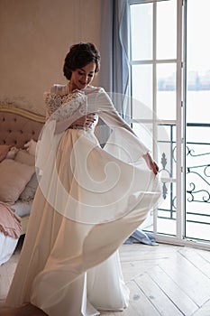 Beautiful bride in a white wedding peignoir in a morning.