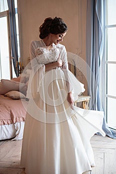 Beautiful bride in a white wedding peignoir in a morning.