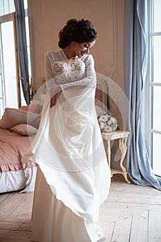 Beautiful bride in a white wedding peignoir in a morning.