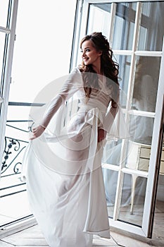 Beautiful bride in a white wedding peignoir in a morning.