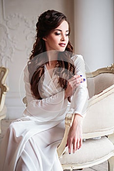 Beautiful bride in a white wedding peignoir in a morning.