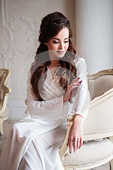 Beautiful bride in a white wedding peignoir in a morning.