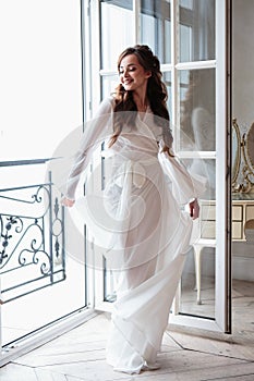 Beautiful bride in a white wedding peignoir in a morning.