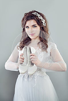 Beautiful bride woman holding white bridal shoes.