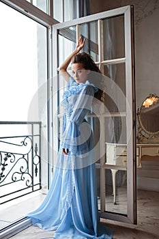 Beautiful bride young woman in a blue long peignoir in a wedding morning