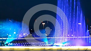 Beautiful bright fountain with illumination and flags at summer dark night