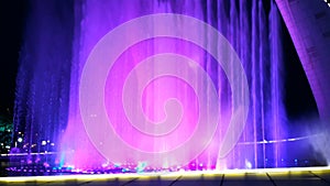 Beautiful bright fountain with illumination and flags at summer dark night