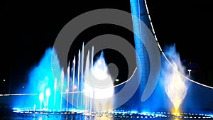 Beautiful bright fountain with illumination and flags at summer dark night