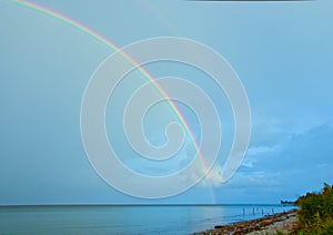 Beautiful, bright, lucent and real rainbow across the ocean