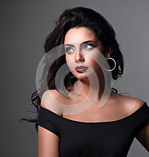 Beautiful bright makeup woman with long black curly volume black hair style, burgundy lipstick with vamp looking up