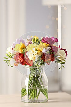 Beautiful bright spring freesia flowers in vase on table.