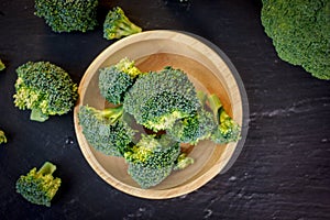 Beautiful broccoli florets on a wooden plate on a slate board.