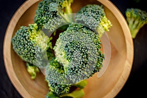 Beautiful broccoli florets on a wooden plate on a slate board.