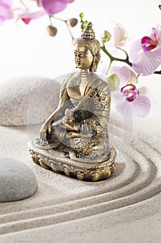 Beautiful bronze Buddha in sand pebble flowers