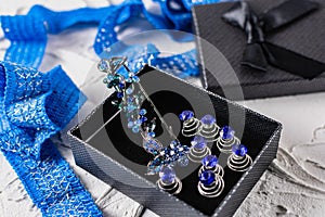 Beautiful brooch with blue and aquamarine stones and rhinestones of different sizes, metal base pins in a gift box with a black bo