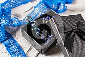 Beautiful brooch with blue and aquamarine stones and rhinestones of different sizes, metal base pins in a gift box with a black bo