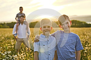 Beautiful brother boy in daisy field on sunset with father on the back