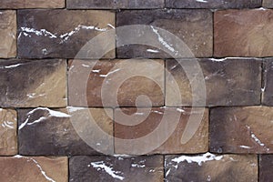 Beautiful brown brown stones bricks, background texture with splashes of snow. Textured material for the construction of facades.