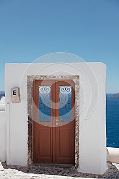 Beautiful brown door on white facade of greek architecture in Oia city, Santorini island, Greece, Europe.