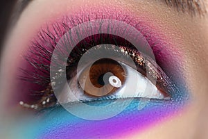 Beautiful brown eye with bright makeup looks up in closeup