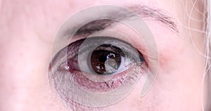 Beautiful brown eye of elderly woman with smoky makeup blinks closeup 4k movie slow motion