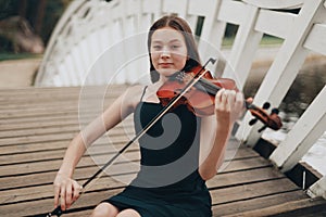 beautiful brown-haired girl of Asian appearance with a violin in nature. musician in nature. classical music