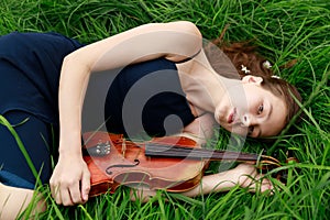beautiful brown-haired girl of Asian appearance with a violin in nature. musician in nature. classical music