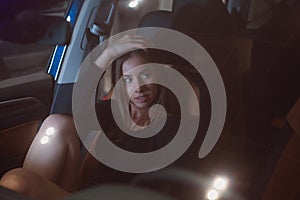 A beautiful brown-haired girl corrects her hair sitting in the salon of a prestigious car photo