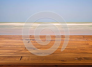 Beautiful brown plank wooden table, little shiny surface, perspective view, the background of the smooth sea wave, blue sky. Empty