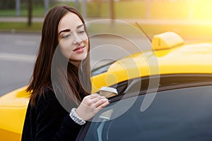 Beautiful brunette in black coat siting in yellow taxi