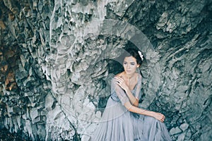 Beautiful brunette bride in a gray dress of tulle and lace near the rock