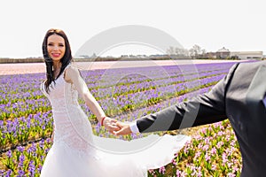 Beautiful brunette bride posing in a field with flowers