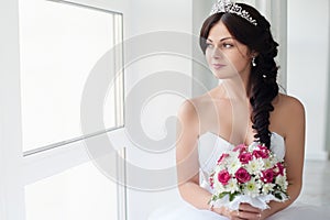 Beautiful brunette bride in a wedding dress and a crown on her head. .