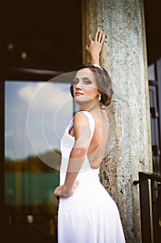 Beautiful brunette bride in white dress walking up stairs