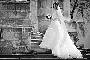 Beautiful brunette bride in white dress walking up stairs,