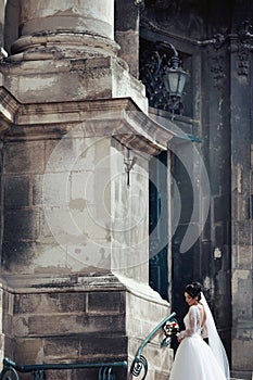 Beautiful brunette bride in white dress walking up stairs,
