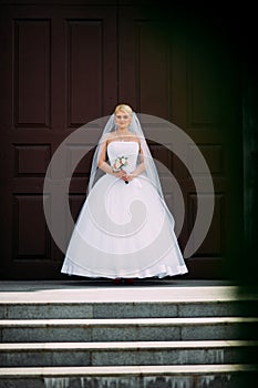 Beautiful brunette bride in white dress walking up stairs