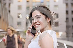 Beautiful brunette business woman in grey smark casual dress working on a mobile phone in her hands outdoors. European city on