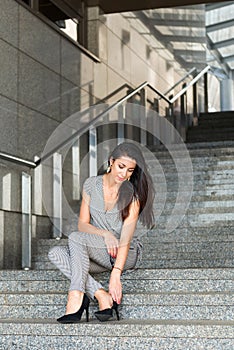 Beautiful brunette businesswoman in gray suit sitting on the stairs