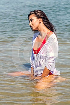 Beautiful brunette Caucasian woman relaxing in shallow water Fashion portrait Summer time Sunny day