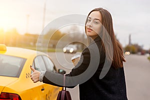 Beautiful brunette with coffee in hand stoping yellow taxi