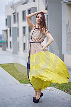 Beautiful brunette in a dress on the street.