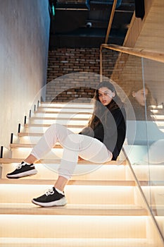 Young beautiful brunette fashion model posing on stairs.